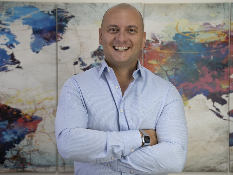 Davide Brioschi, Founder e CEO di B group, davanti a una mappa del mondo dipinta